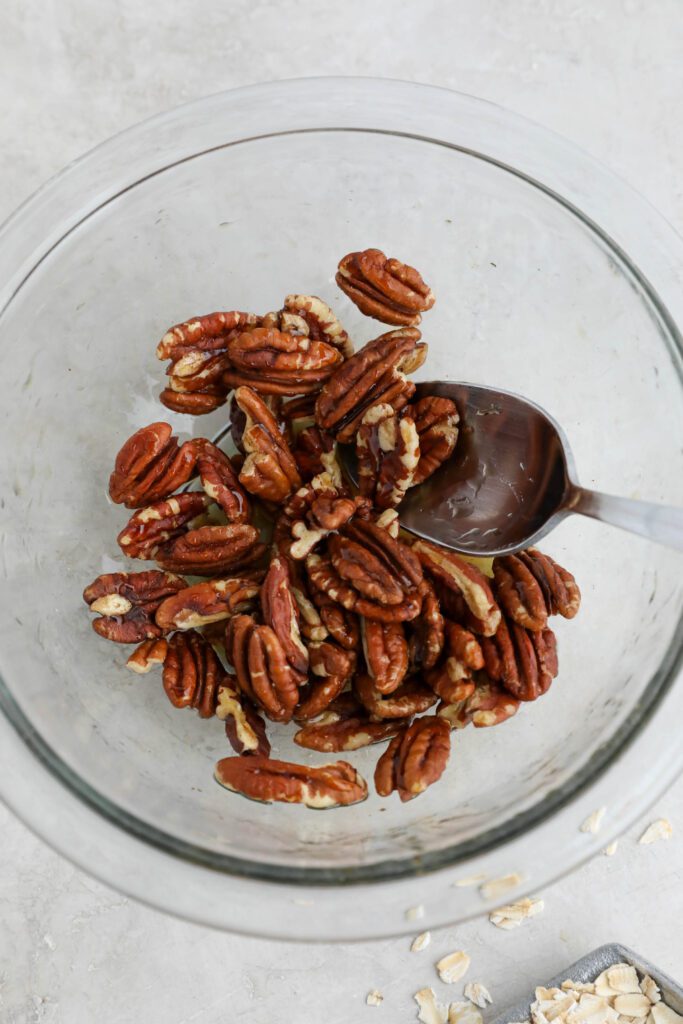 pecans in bowl tossed with maple syrup