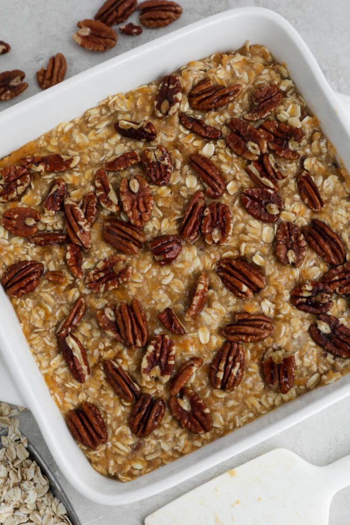 sweet potato pie baked oats in baking dish topped with candied pecans 