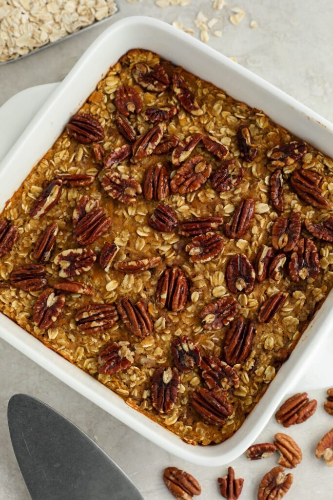 Sweet Potato Pie Baked Oatmeal served in casserole dish with pie server with pecans and oats 