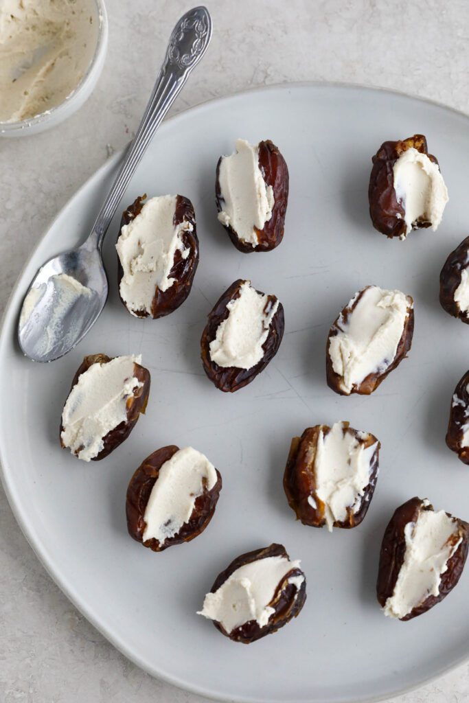 Dates with cream cheese in the center on plate with spoon