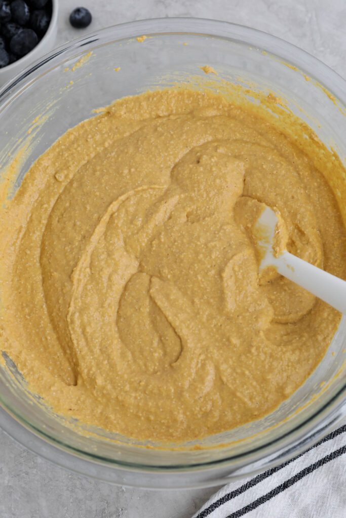 ingredients for sweet potato waffles in glass bowl with spatula 