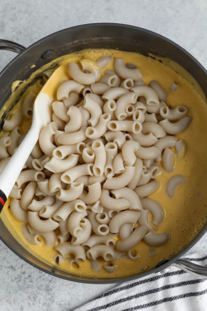macaroni in butternut cheese sauce in pot with spatula