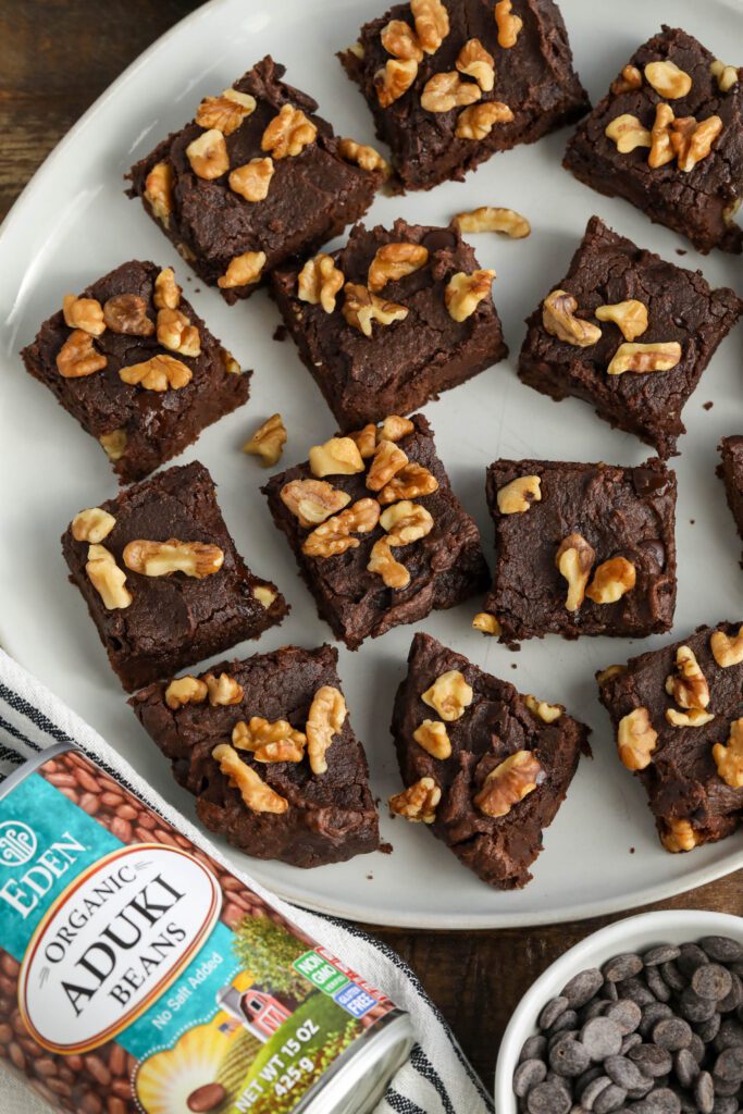 Red Bean Brownies cut into squares on plate with bowl of chocolate chips and can of Aduki Beans