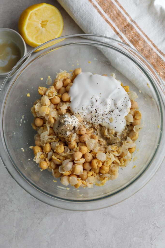 ingredients for chickpea salad mixed in glass bowl