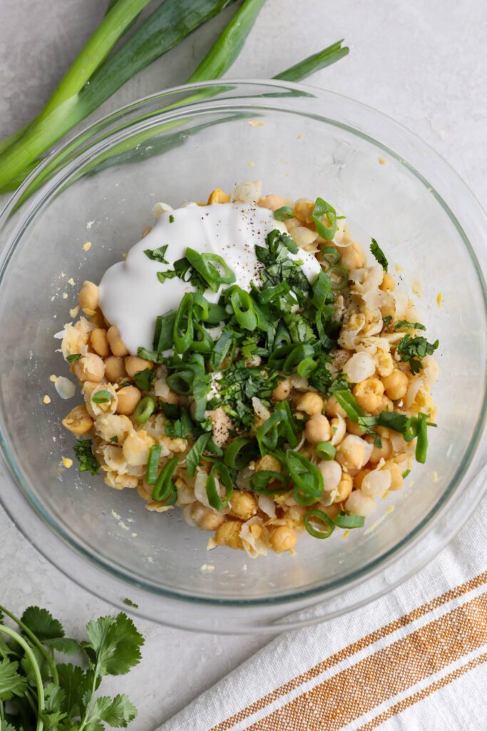 chickpea salad ingredients in bowl topped with cilantro and spring onion