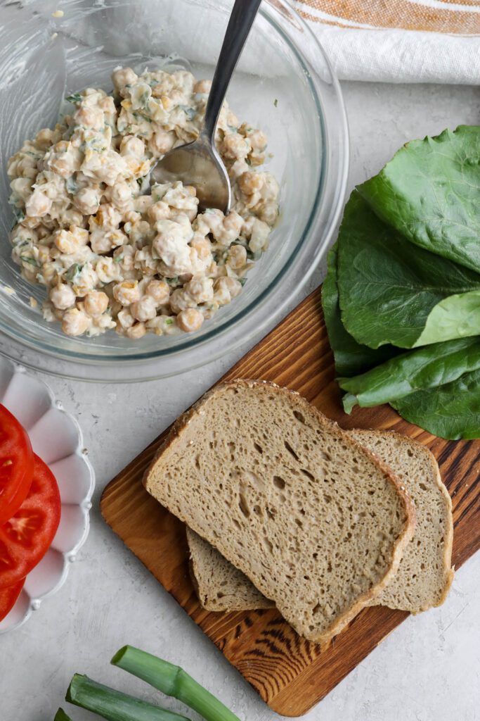 Vegan Chickpea Salad in bowl with board and lettuce and tomato