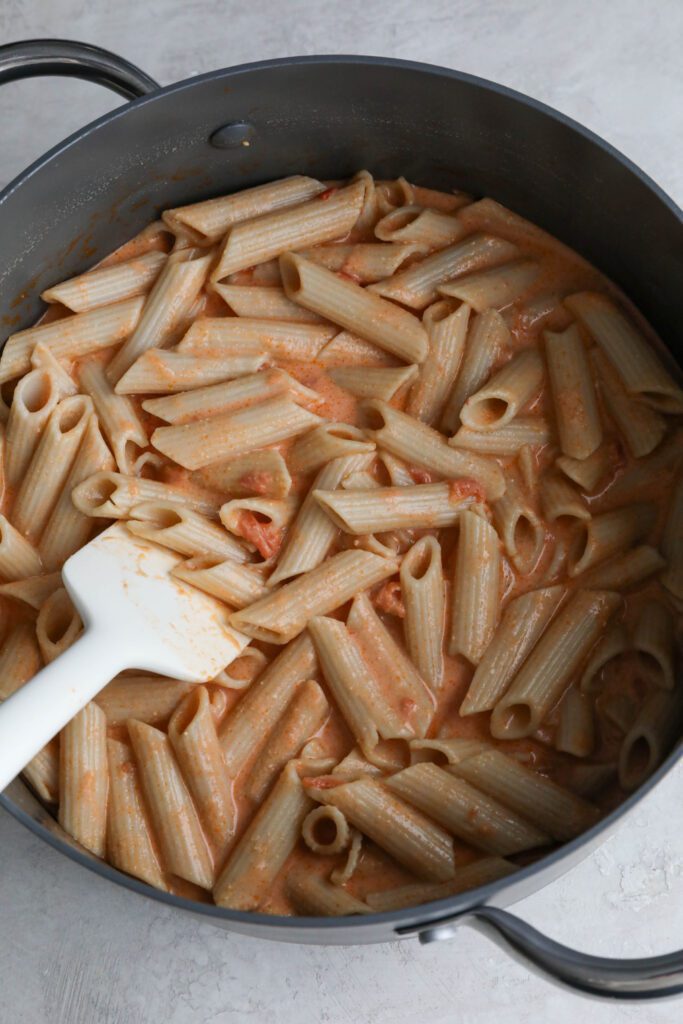 pink pasta mixed in pot in spatula 