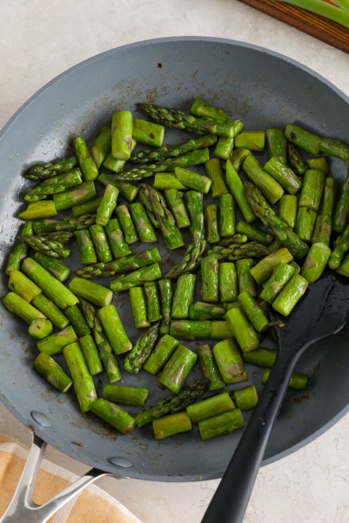 asparagus sautéed in pan with spatula 