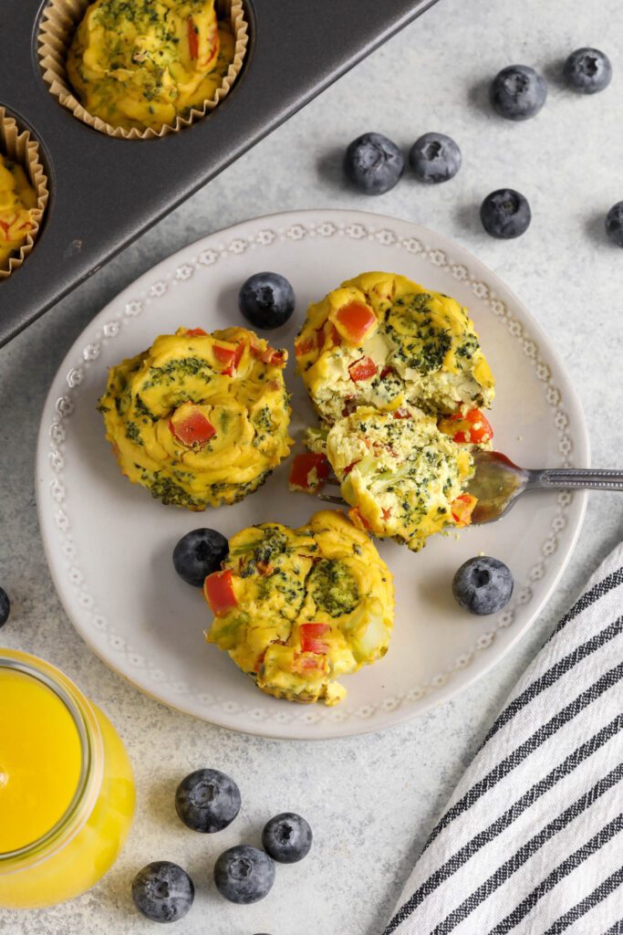 Tofu "Egg" Cups served on white plate with fork and blueberries with glass of orange juice