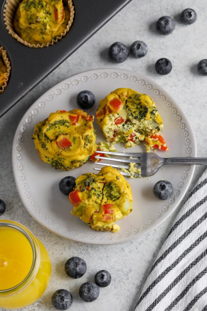 Tofu "Egg" Cups served on white plate with fork and blueberries with glass of orange juice