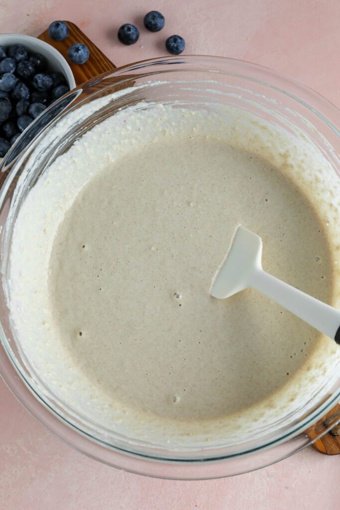 applesauce waffles batter in bowl with spatula with blueberries on the side 