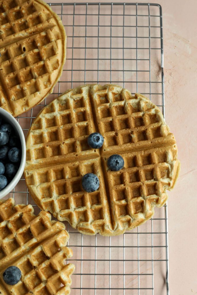 Vegan Applesauce Waffles on cooling rack topped with blueberries