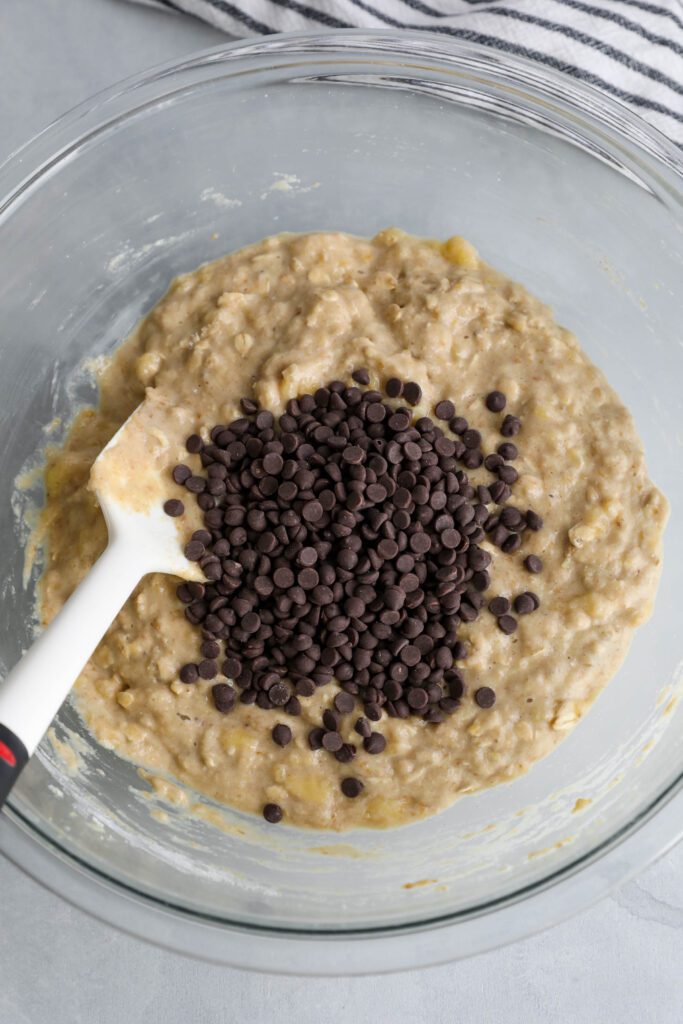 Banana Oatmeal Chocolate Chips Muffin batter in bowl with chocolate chips and spatula