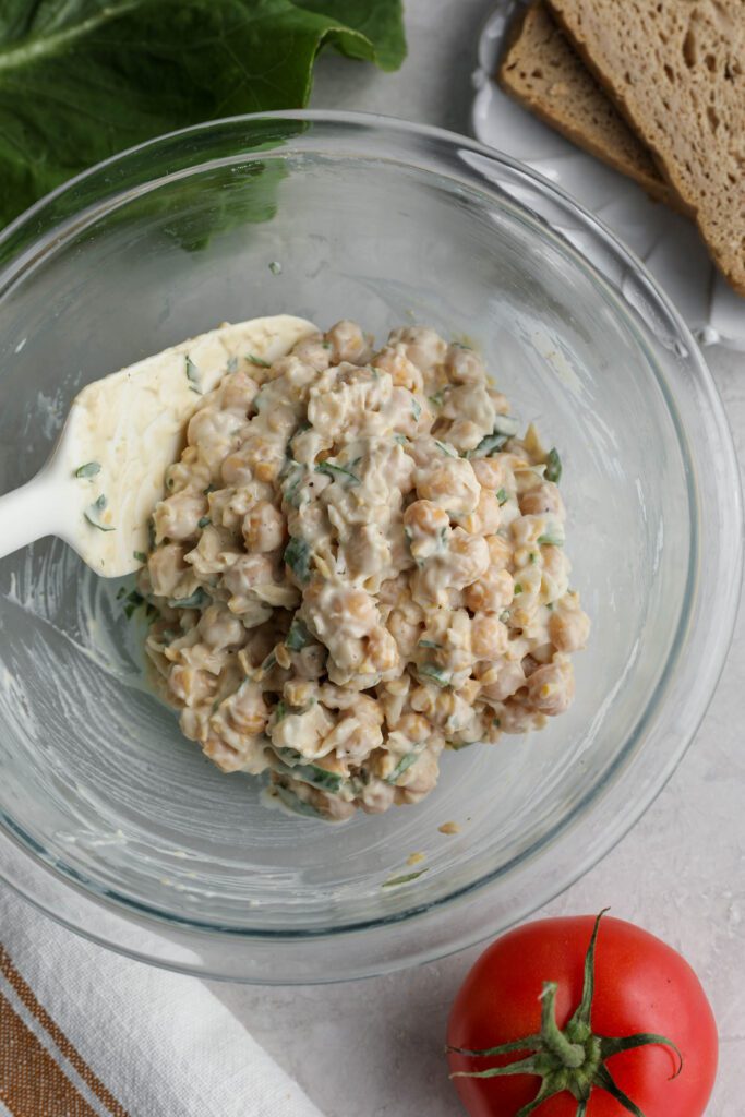 Vegan Chickpea Salad Sandwich ingredients mixed in bowl with spatula