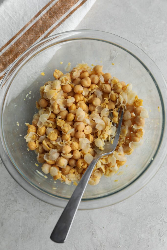 chickpeas smashed in glass bowl with fork and towel