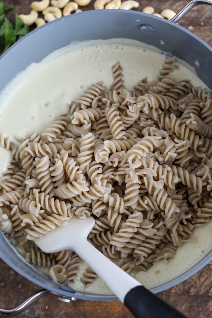 cooked pasta with cauliflower alfredo sauce with spatula in pot 