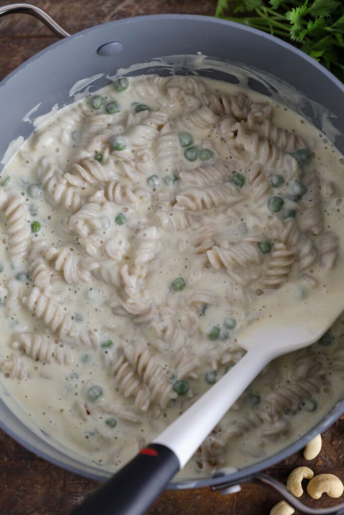 Cauliflower Cashew Alfredo served in pot with spatula with peas