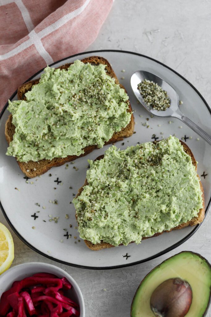 Smashed Edamame Dip spread on toast topped with hemp seeds
