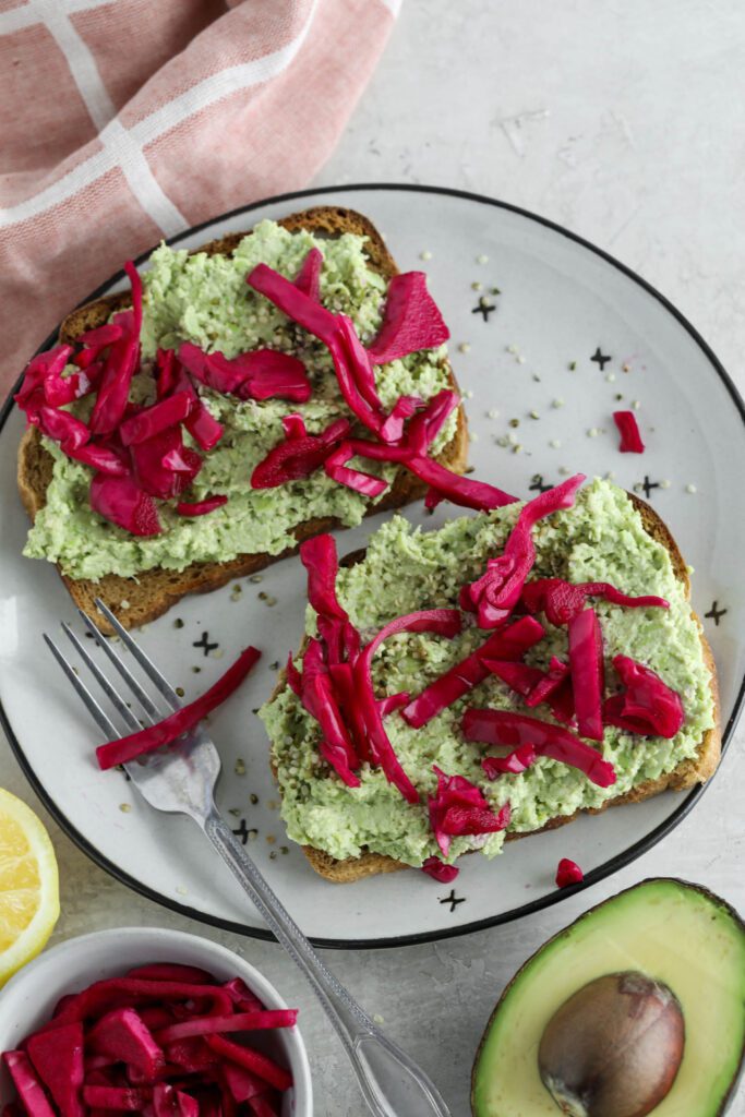 Smashed Edamame Toast served on plate topped with pickled cabbage 