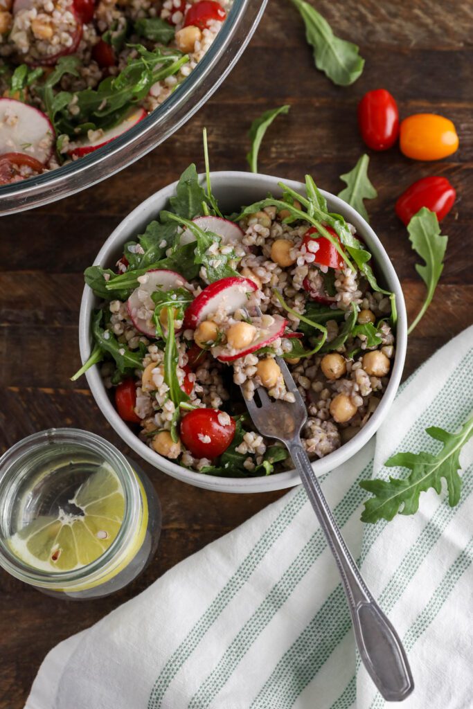 Spring Buckwheat Tabbouleh in bowl with arugula and cherry tomatoes on the side