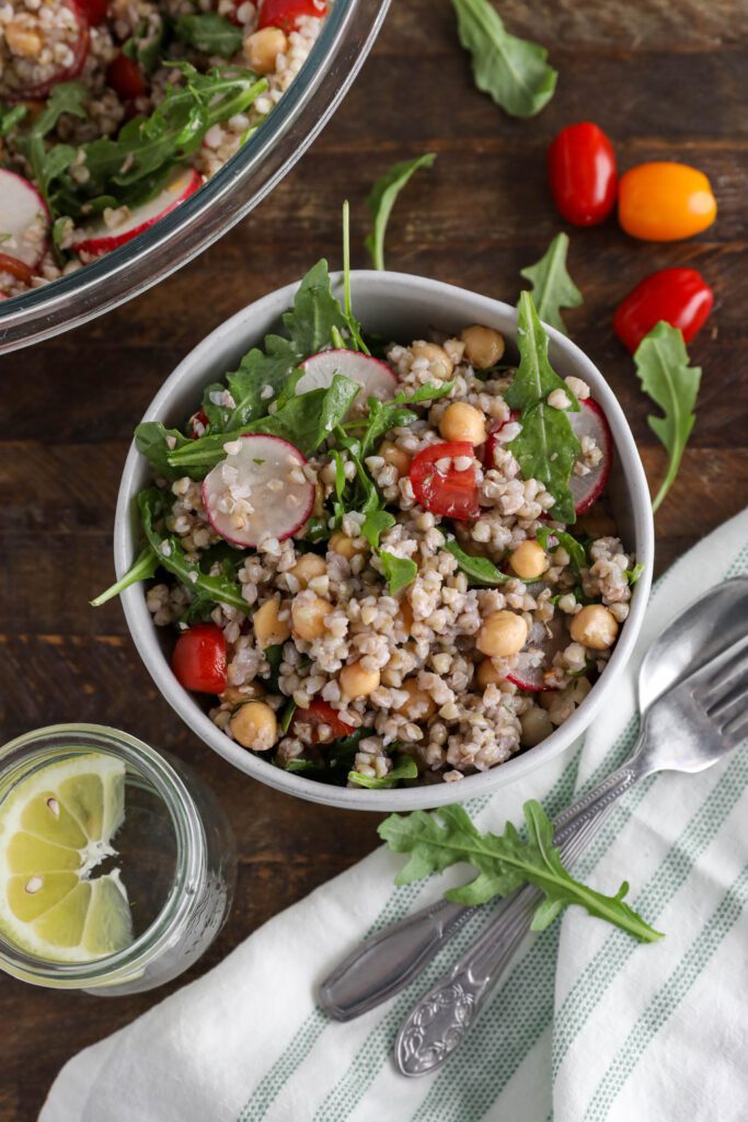 Spring Buckwheat Tabbouleh in bowl with arugula and cherry tomatoes on the side