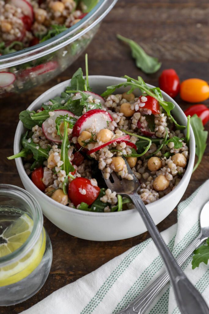 Spring Buckwheat Tabbouleh in bowl with arugula and cherry tomatoes on the side
