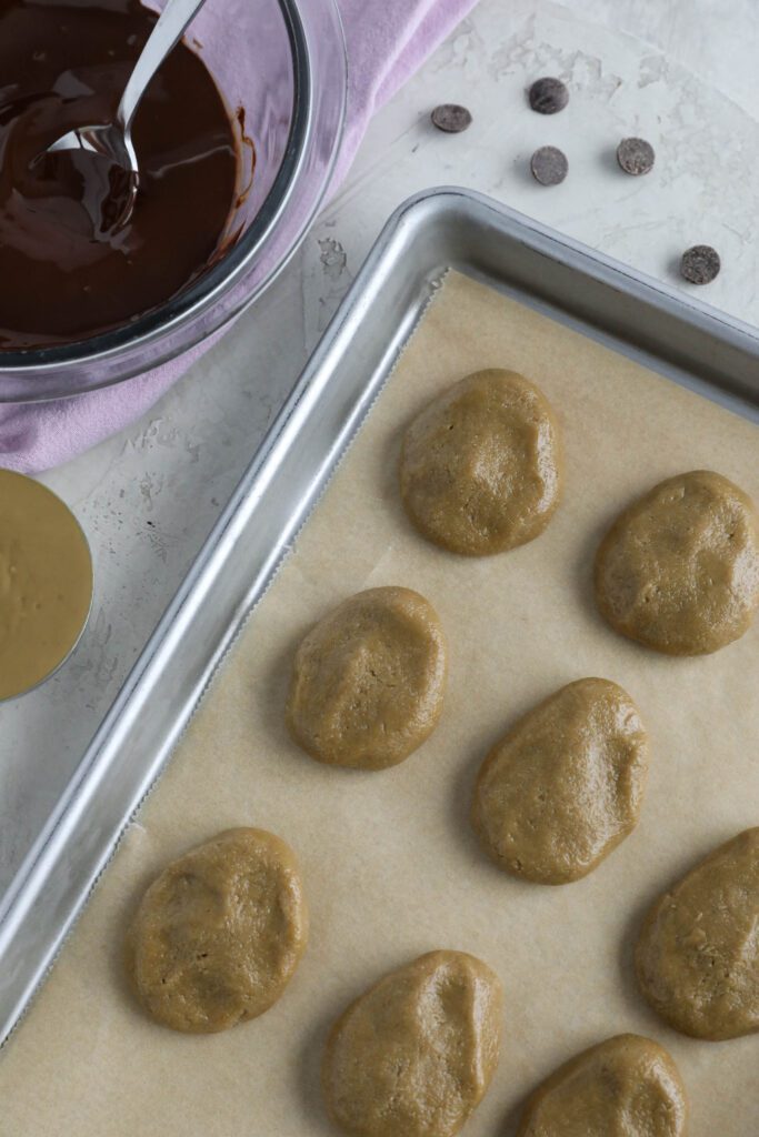 SunButter Easter eggs on baking sheet with melted chocolate on the side