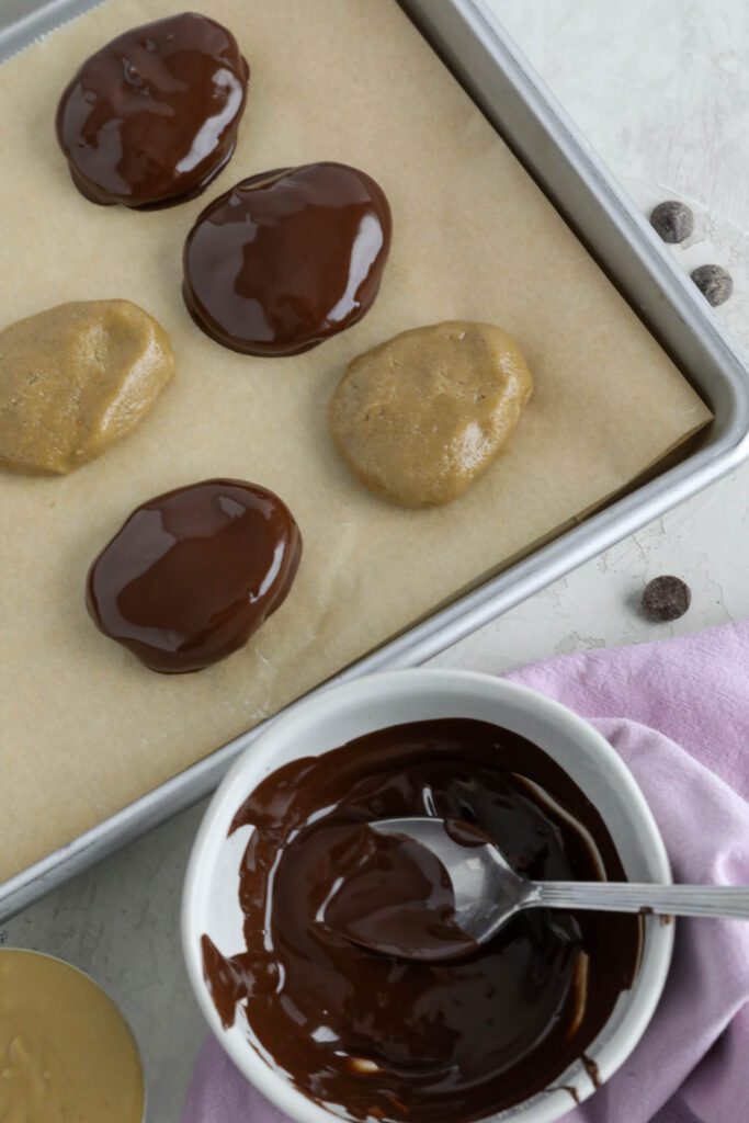 SunButter Chocolate Easter Eggs dipped in melted chocolate on parchment lined baking sheet