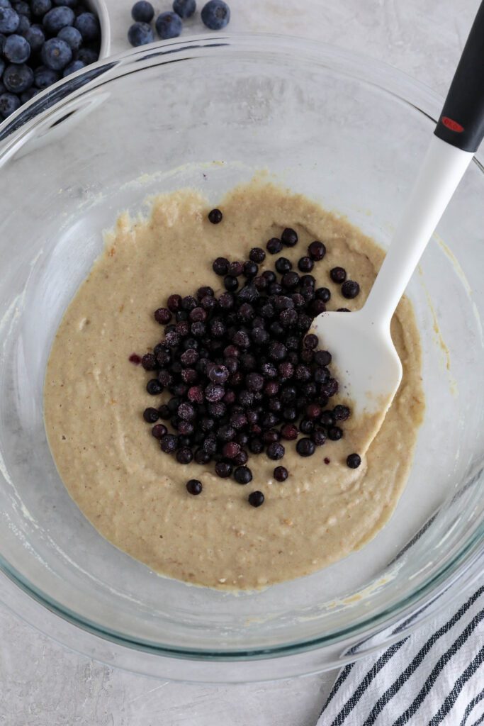 batter for vegan blueberry muffins with frozen blueberries mixed in with spatula 