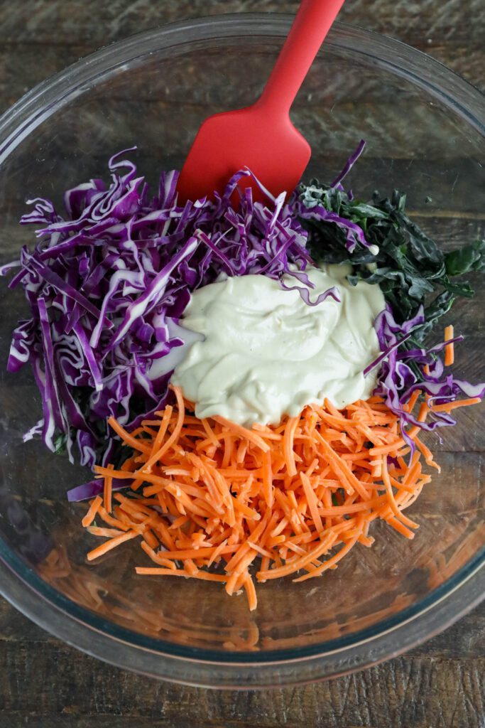 tahini slaw ingredients in bowl with red spatula 