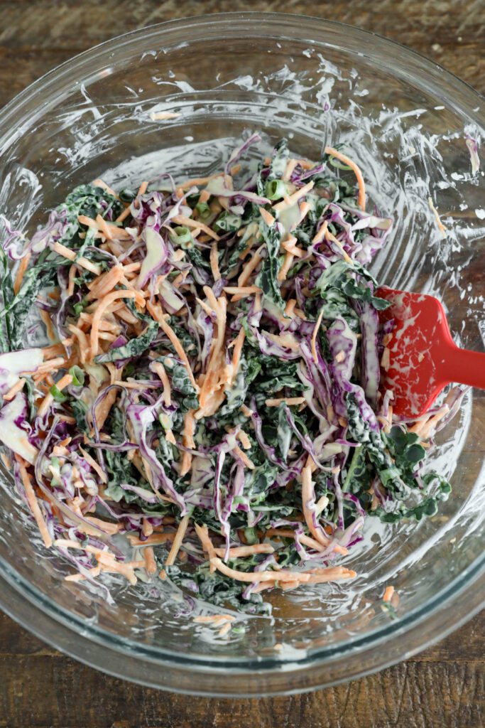 Tahini slaw mixed in large bowl with red spatula 