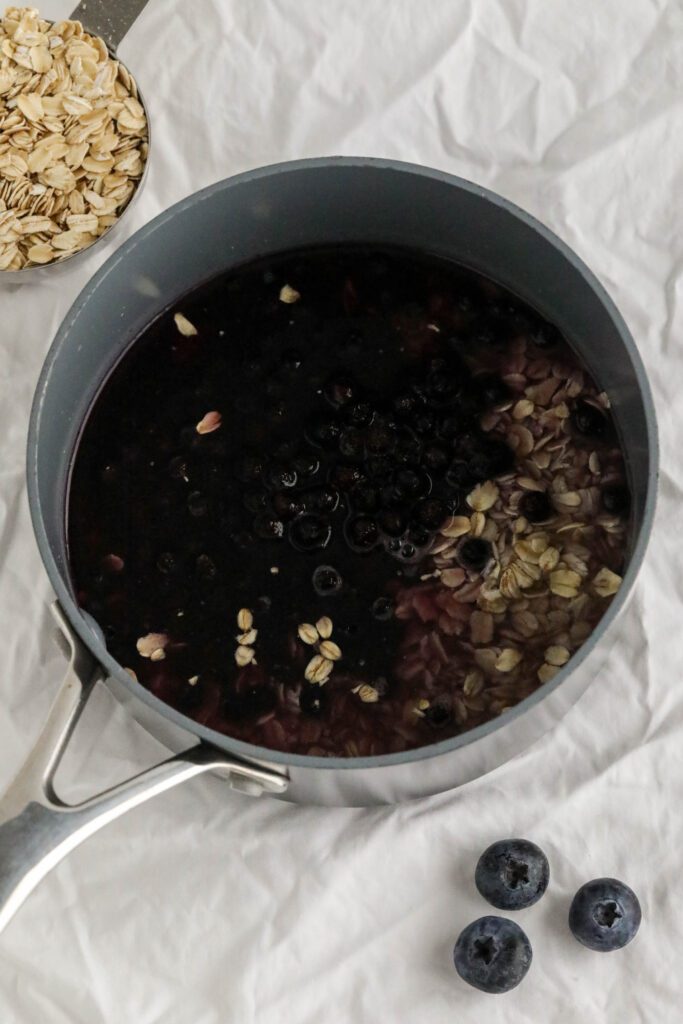 ingredients for blueberry stovetop oatmeal in pot on white towel 