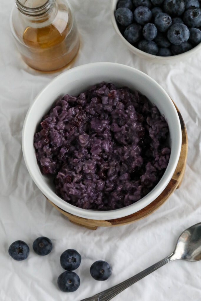 Blueberry Stovetop Oatmeal served in bowl on wooden pedestal with scattered blueberries
