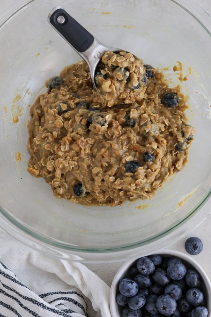Blueberry SunButter Breakfast Cookie batter scooped with 1/4 cup scoop with blueberries on the side 