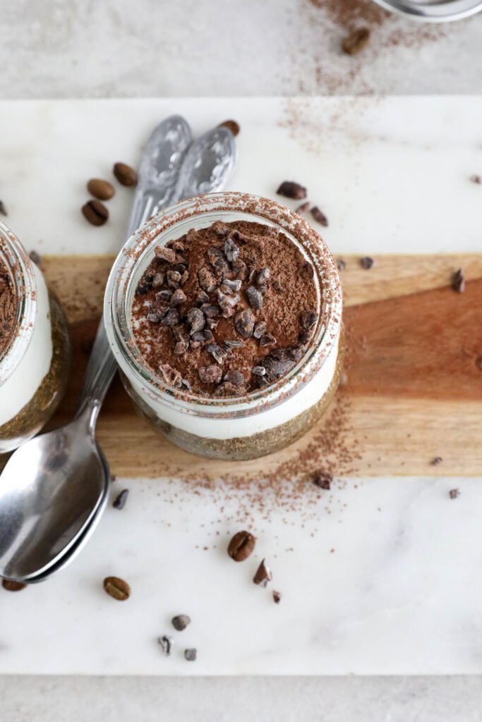 Viral Tiramisu Chia Pudding served in weck jars with two spoons surrounded by cacao nibs and coffee beans 