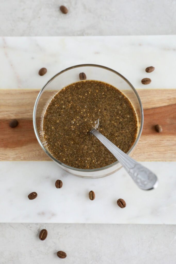 Tiramisu Chia Pudding mixed in jar with spoon on marble board