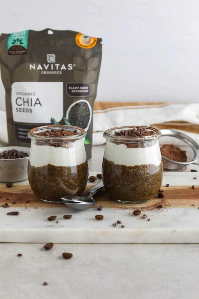 Viral Tiramisu Chia Pudding served in weck jars with two spoons surrounded by cacao nibs and coffee beans 