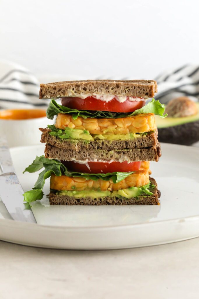 Buffalo Tempeh Sandwich stacked on white plate