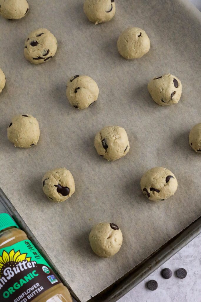 chocolate chip snack cookie batter rolled into balls on parchment lined baking sheet