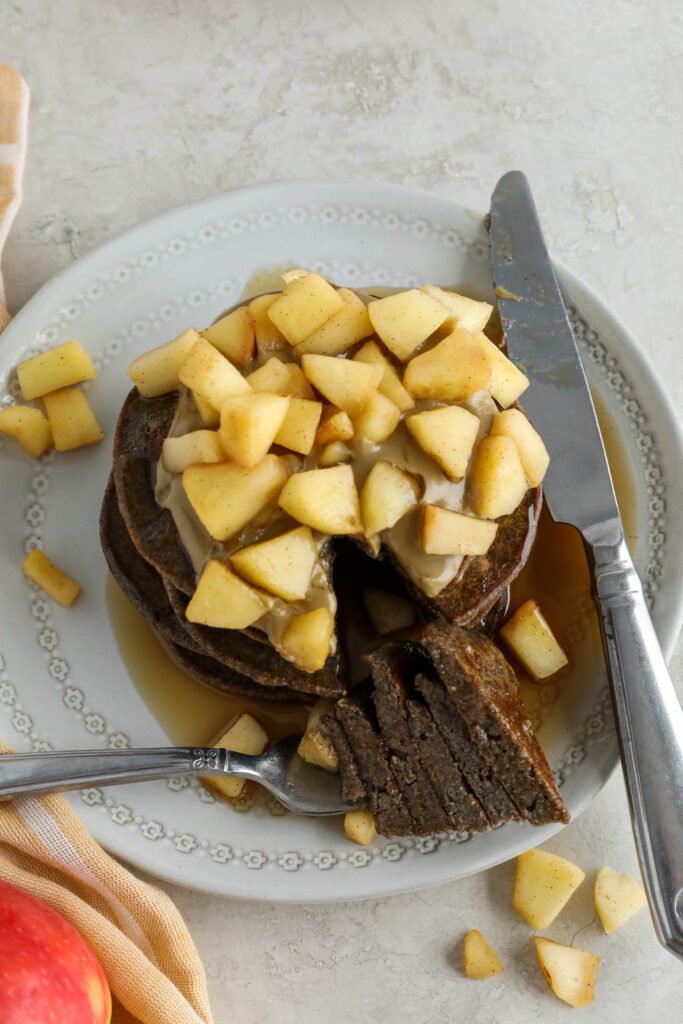 Vegan Apple Pie Pancakes served on plate topped with apple compote and maple syrup