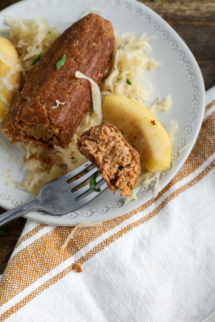 Vegan bratwurst on plate topped with sauerkraut