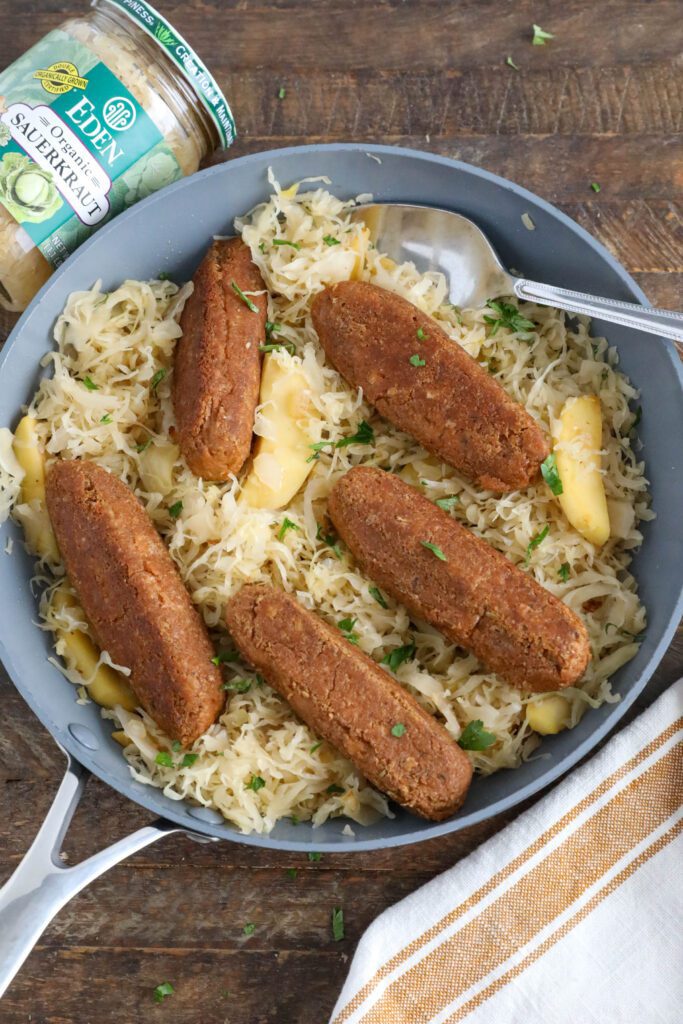 Vegan Bratwurst with Sauerkraut in pan with spoon topped with parsley