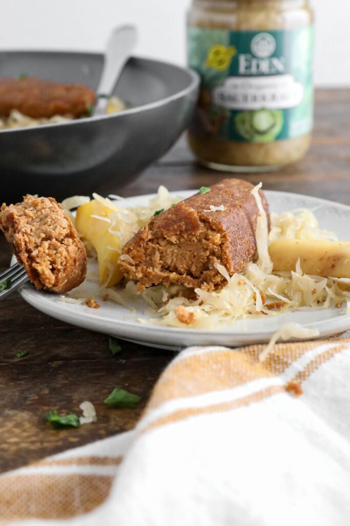 Vegan bratwurst on plate topped with sauerkraut