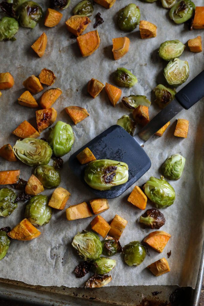 roasted brussels sprouts and sweet potato on parchment lined baking sheet