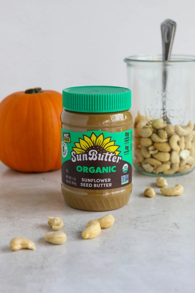 SunButter jar on board with cashews and pumpkin behind it 