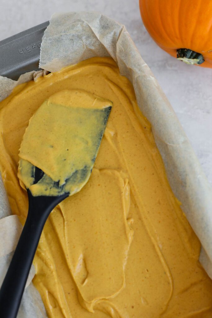pumpkin pie filling spread on top off crust in bread pan
