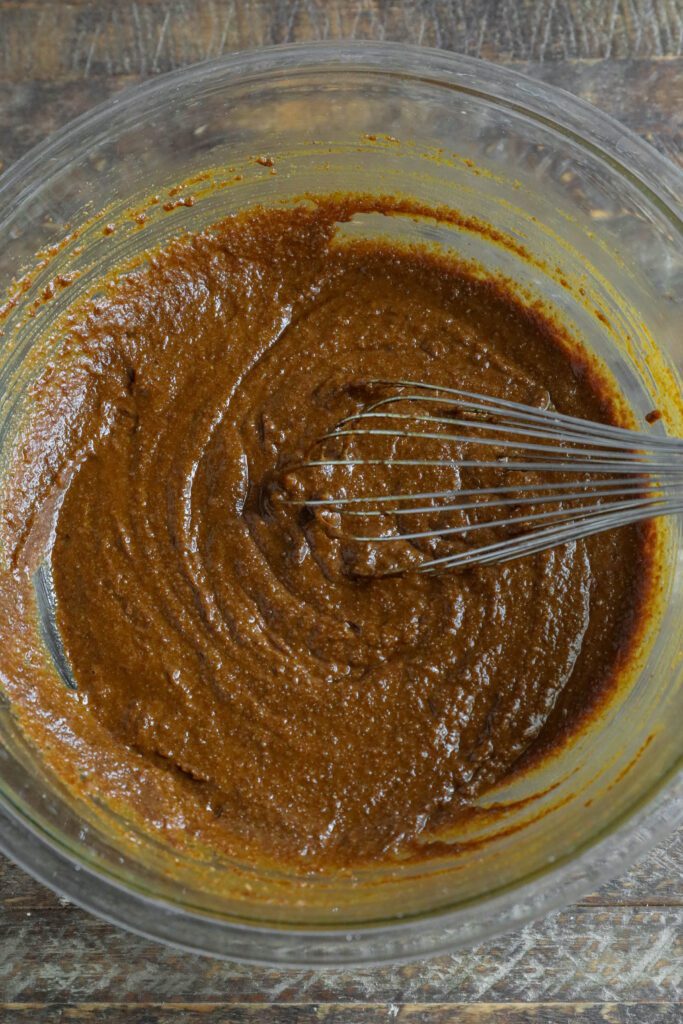 ingredients for gingerbread loaf mixed together in bowl with whisker 