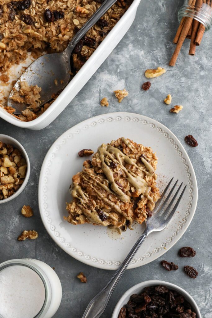 Cinnamon Raisin Cookie Baked Oatmeal served on plate topped with SunButter and maple syrup and cinnamon with a fork