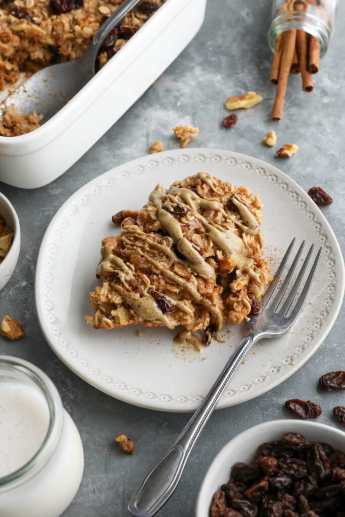 Cinnamon Raisin Cookie Baked Oatmeal served on plate topped with SunButter and maple syrup and cinnamon with a fork