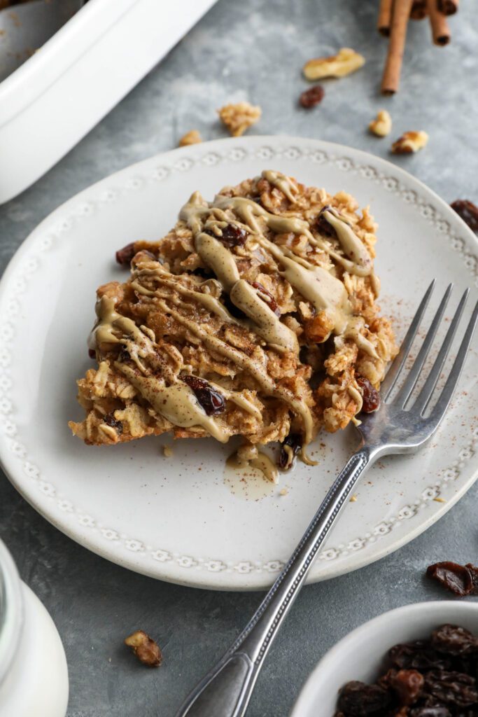 Cinnamon Raisin Cookie Baked Oatmeal served on plate topped with SunButter and maple syrup and cinnamon with a fork